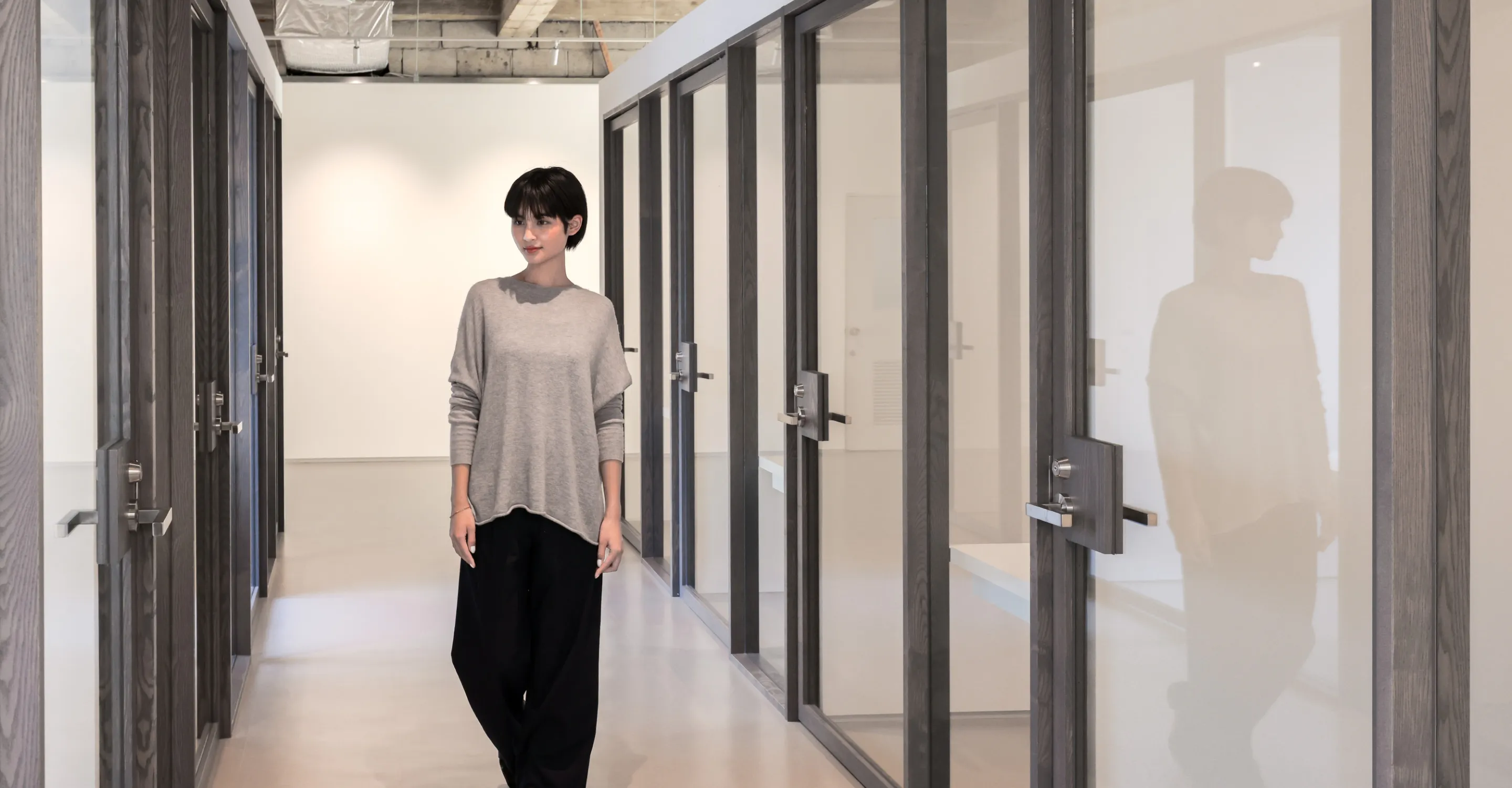 写真。プライベートオフィスの廊下を歩く女性