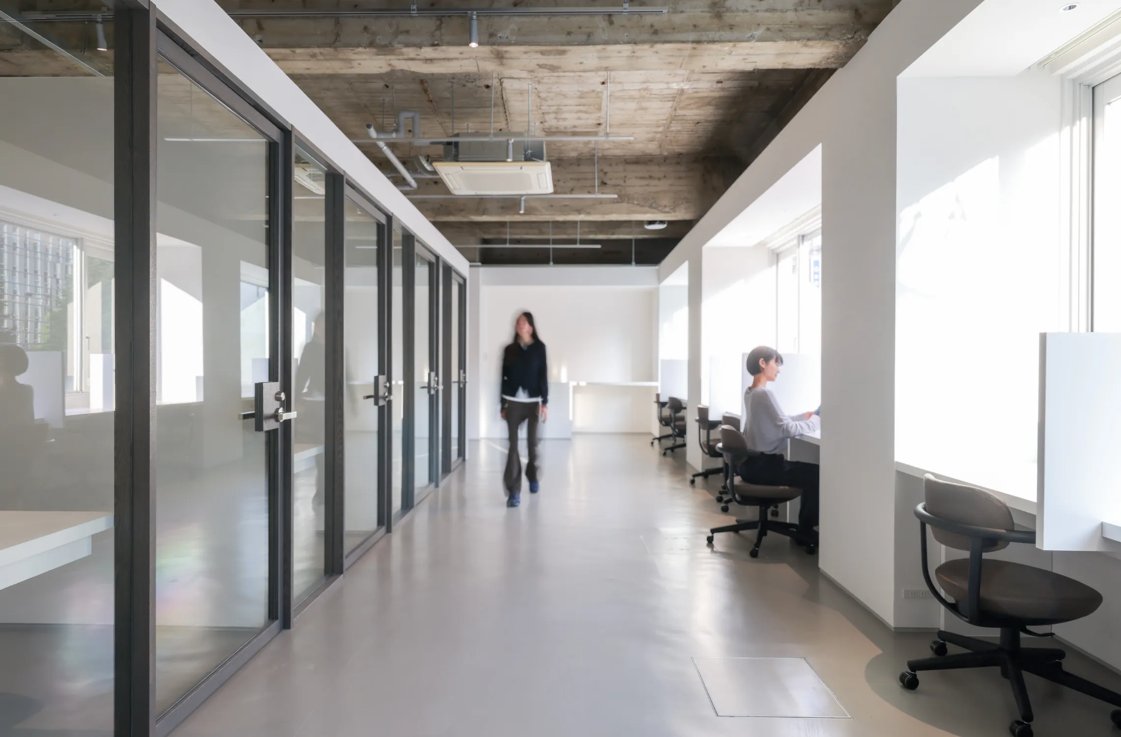 写真。窓際の仕切りがあるデスクとプライベートオフィスを利用しているユーザーのイメージ図